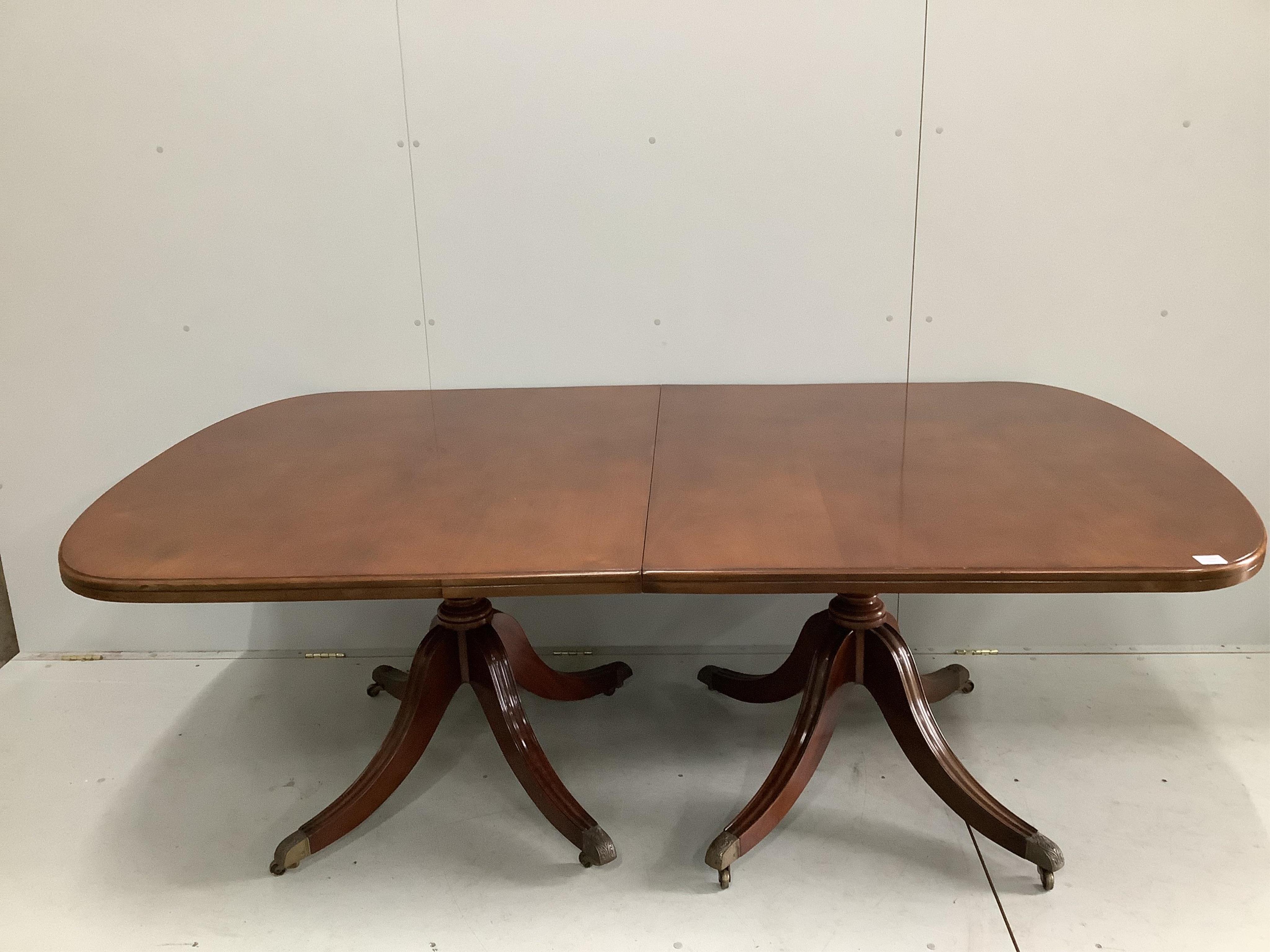 A reproduction George III style mahogany twin pillar extending dining table, 264cm extended, one spare leaf, width 121cm, height 73cm. Condition - good